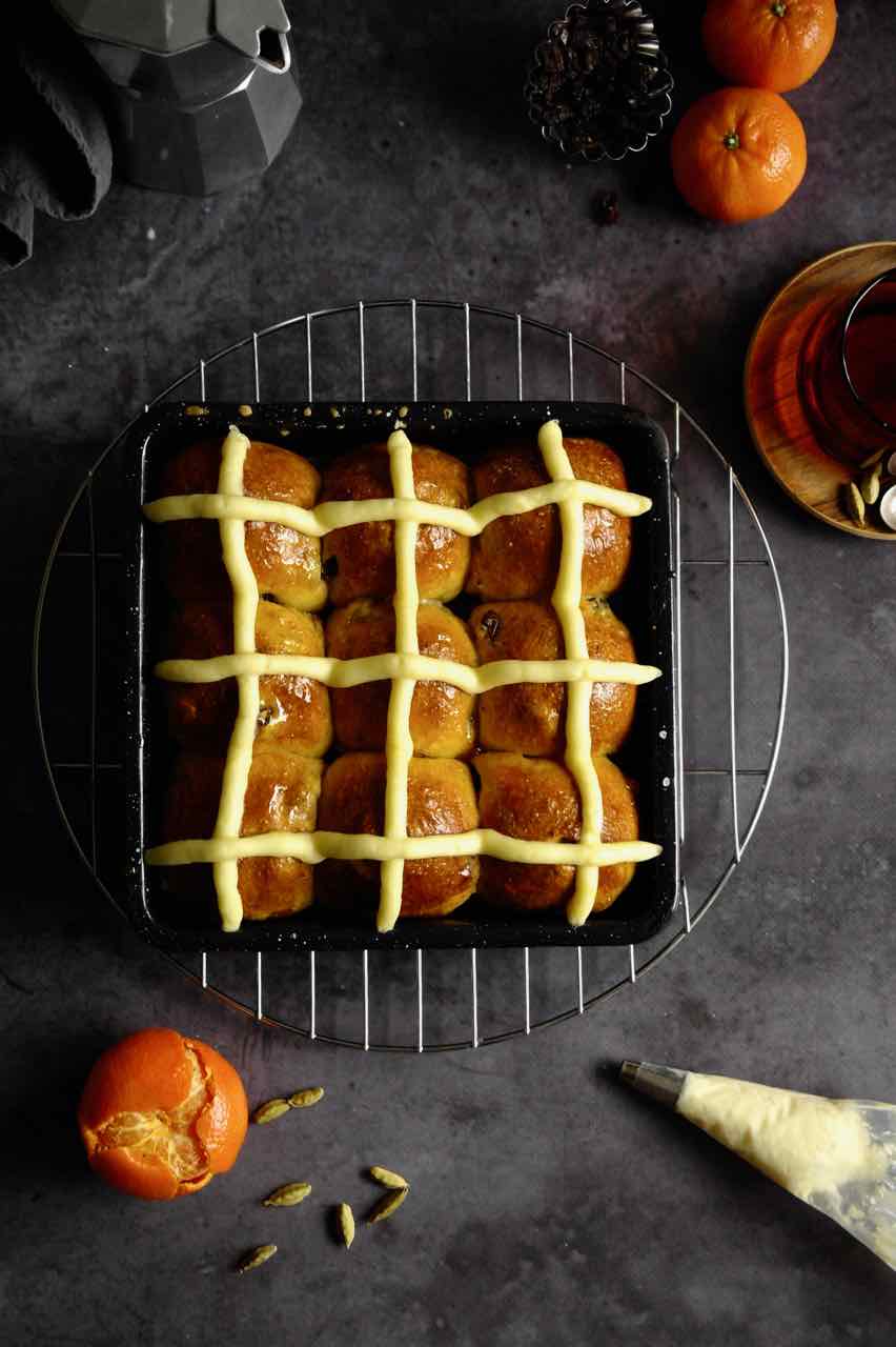 Hot cross buns in a square pan on a dark surface